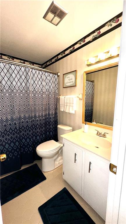 bathroom with toilet, tile patterned flooring, vanity, and a shower with shower curtain