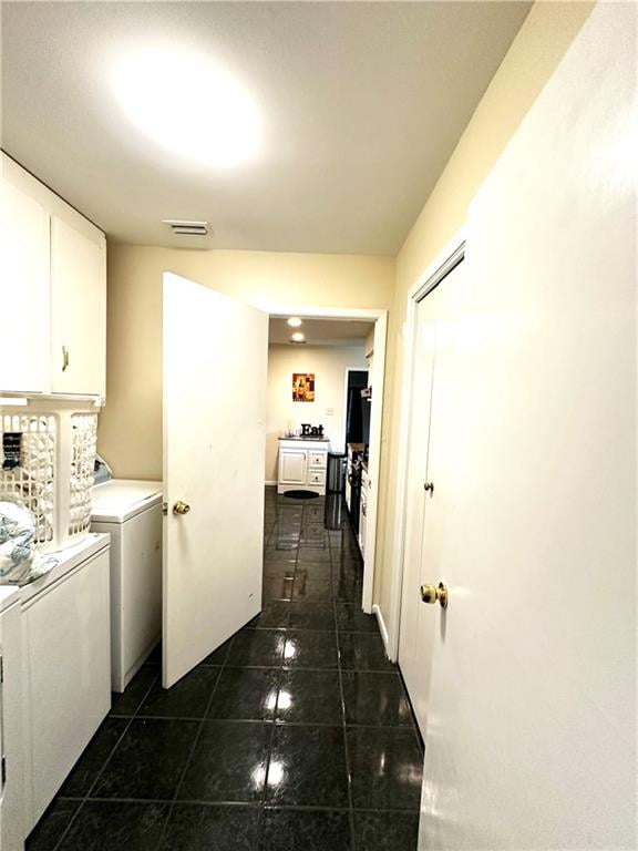 clothes washing area with cabinets, dark tile patterned flooring, and washing machine and dryer