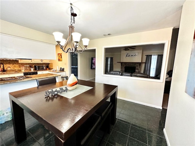 dining space with a fireplace and a notable chandelier