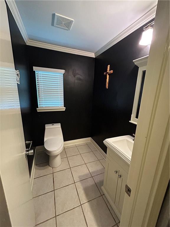 9016 Julie St, Mobile, AL 36608 - half bathroom with tile patterned floors, toilet, ornamental molding, vanity, and baseboards