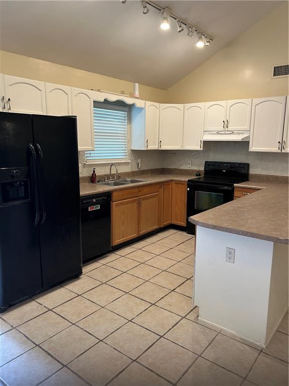 9016 Julie St, Mobile, AL 36608 - kitchen with black appliances, under cabinet range hood, track lighting, vaulted ceiling, and light tile patterned floors