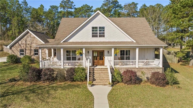 farmhouse inspired home with roof with shingles, covered porch, and a front lawn