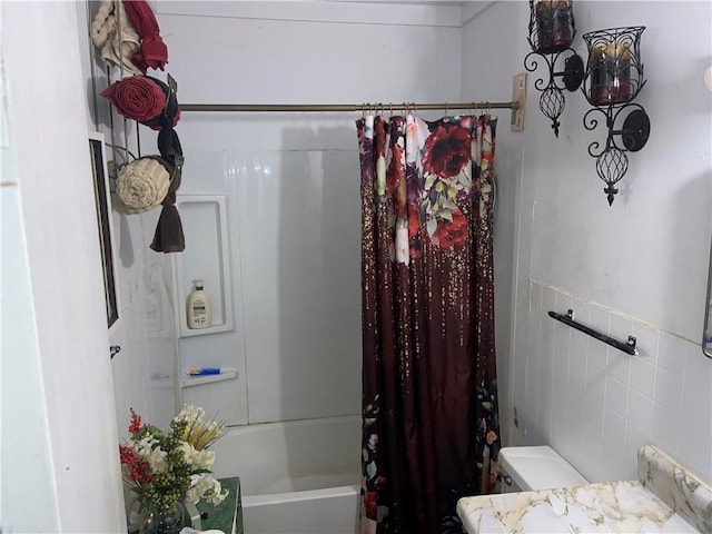 bathroom featuring tile walls, shower / bath combo with shower curtain, and toilet