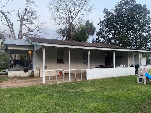 back of property with covered porch and a yard