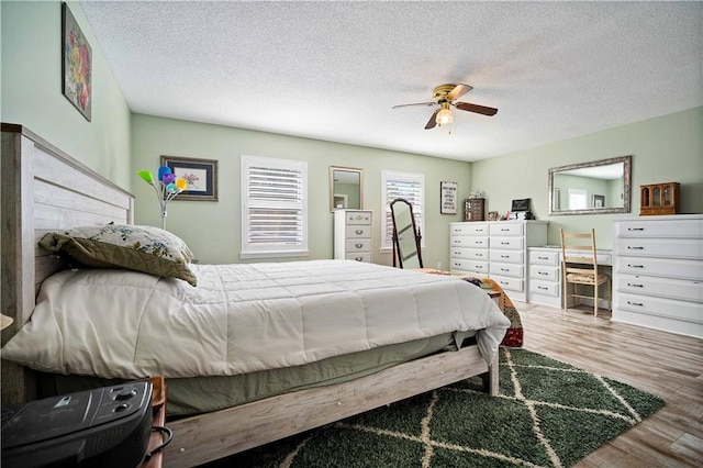 bedroom featuring ceiling fan, hardwood / wood-style floors, and a textured ceiling