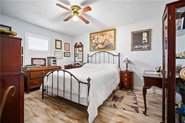 bedroom with a textured ceiling, light hardwood / wood-style floors, and ceiling fan