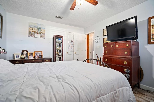 bedroom with ceiling fan, hardwood / wood-style floors, and a textured ceiling