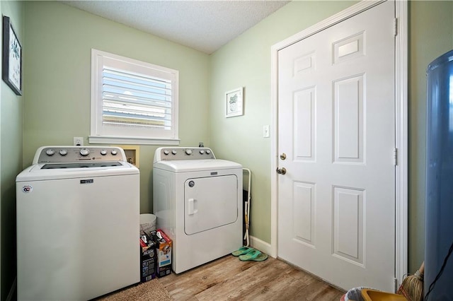 laundry area with washer and clothes dryer, light hardwood / wood-style floors, and a textured ceiling