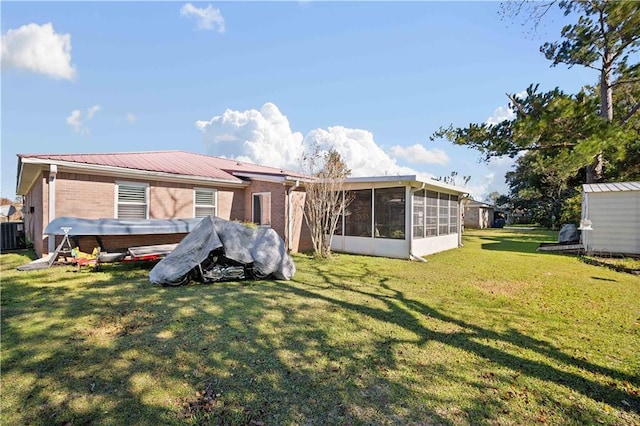 rear view of house featuring a sunroom, a yard, and central AC