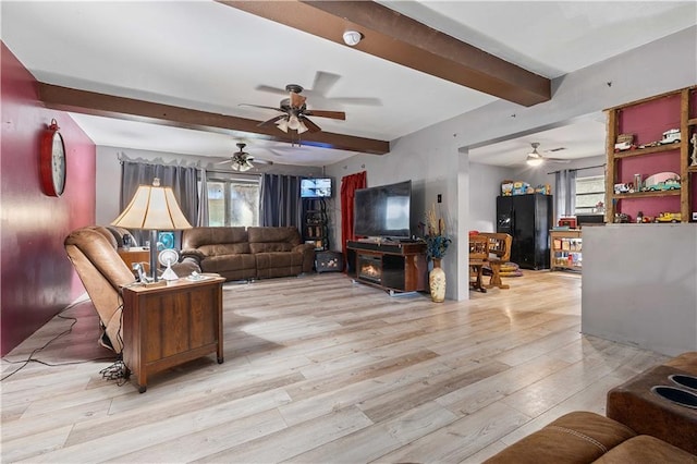 living room featuring light wood-type flooring, a wealth of natural light, a fireplace, and beam ceiling