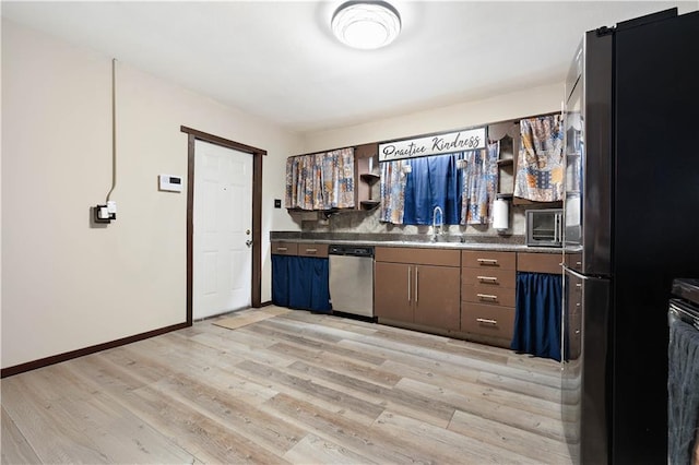 kitchen with sink, dishwasher, black refrigerator, dark brown cabinets, and light wood-type flooring