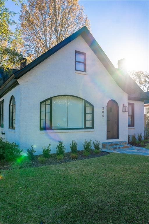 view of front of home featuring a chimney and a front lawn