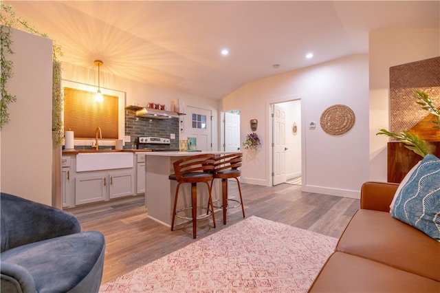 living area with baseboards, recessed lighting, wood finished floors, and lofted ceiling