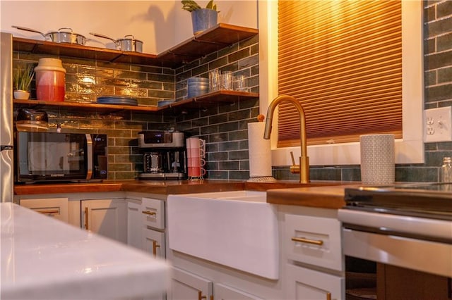 interior space with tasteful backsplash, black microwave, white cabinetry, and butcher block countertops