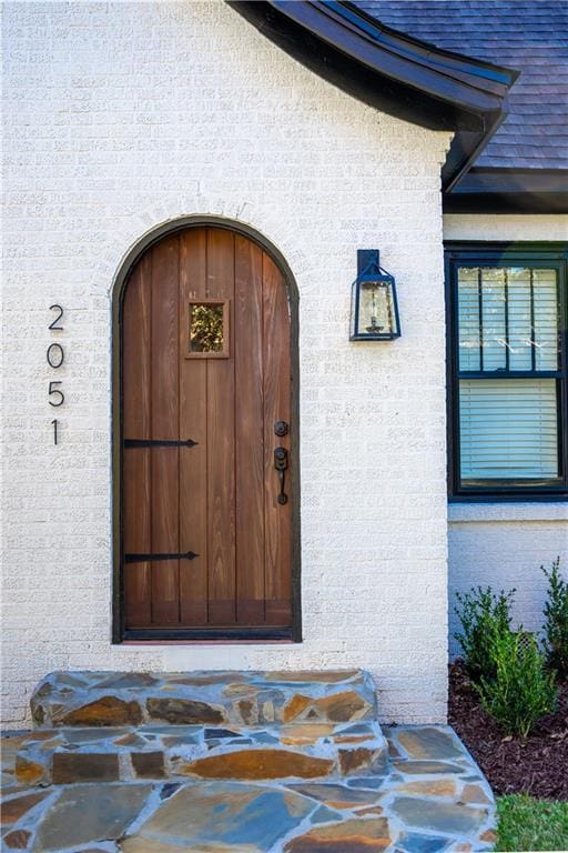 property entrance featuring stucco siding and roof with shingles