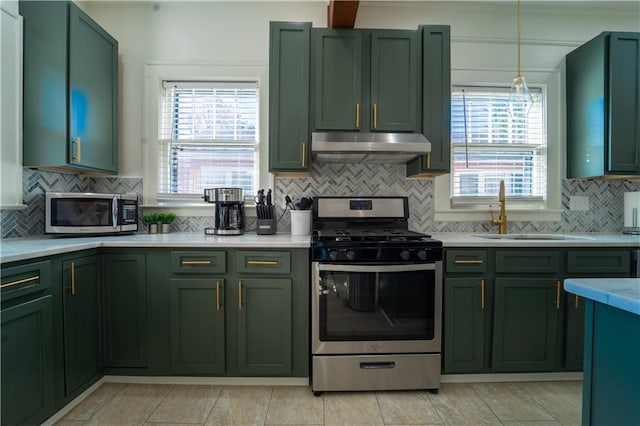kitchen with light countertops, under cabinet range hood, appliances with stainless steel finishes, green cabinetry, and a sink