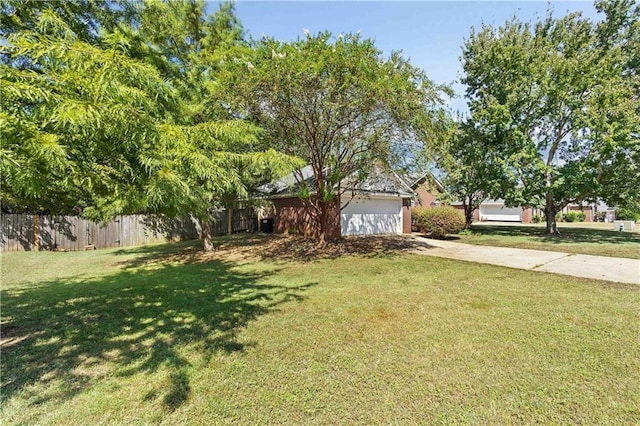 view of property hidden behind natural elements featuring a garage and a front yard