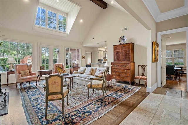 living room with beam ceiling, visible vents, ornamental molding, high vaulted ceiling, and baseboards