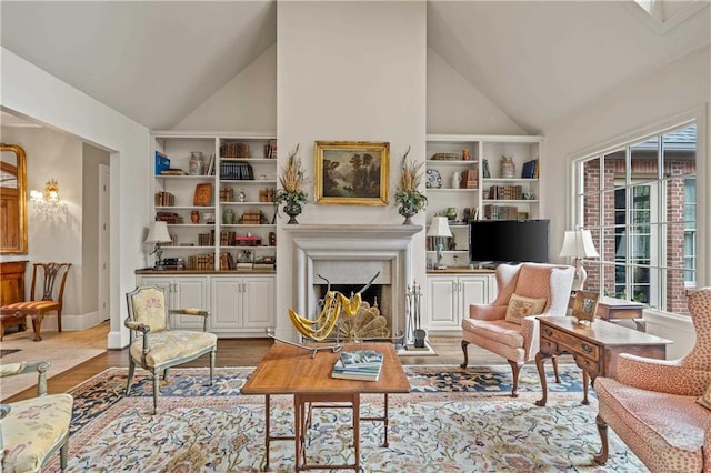 sitting room with built in features, light wood-style floors, a high end fireplace, high vaulted ceiling, and baseboards