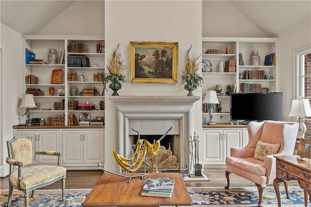 sitting room featuring vaulted ceiling, a fireplace, and wood finished floors