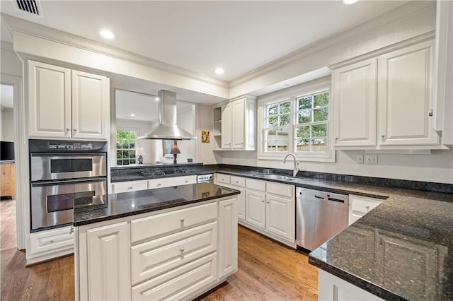 kitchen featuring island range hood, appliances with stainless steel finishes, white cabinets, and a sink