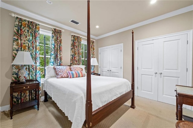 bedroom featuring baseboards, visible vents, light colored carpet, ornamental molding, and two closets