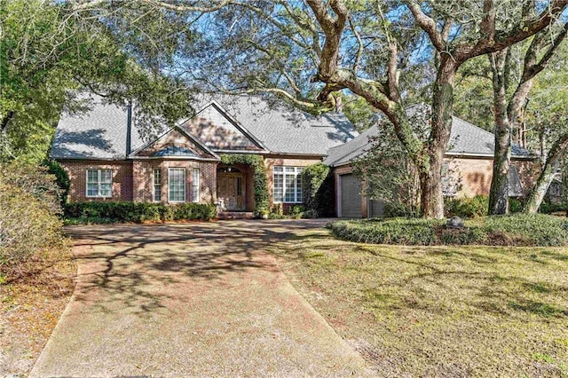 view of front facade with a front yard, brick siding, driveway, and an attached garage