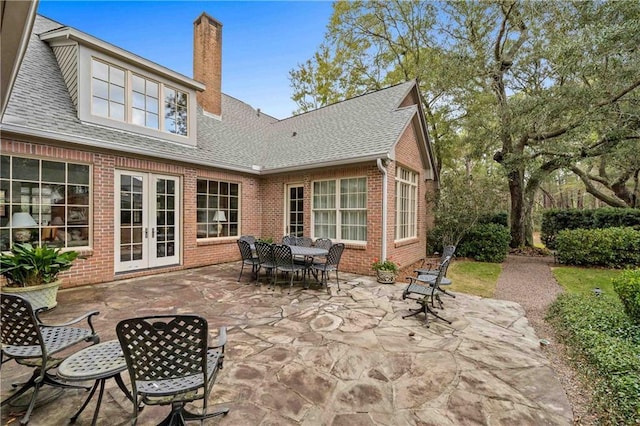 back of house featuring a shingled roof, french doors, and brick siding