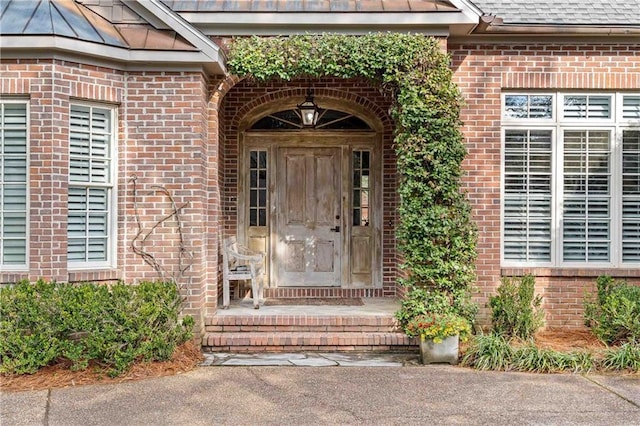 property entrance with a standing seam roof, brick siding, metal roof, and roof with shingles