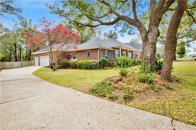 single story home featuring brick siding, a front yard, an attached garage, and driveway
