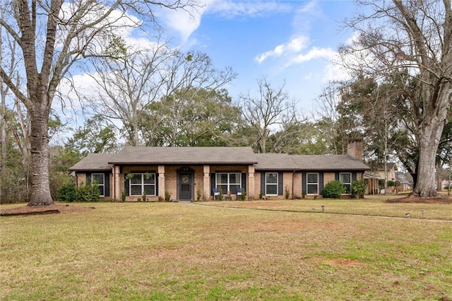 single story home with brick siding, a chimney, and a front yard