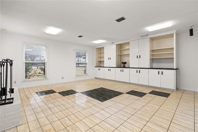 exercise room featuring light tile patterned flooring, built in features, visible vents, and baseboards