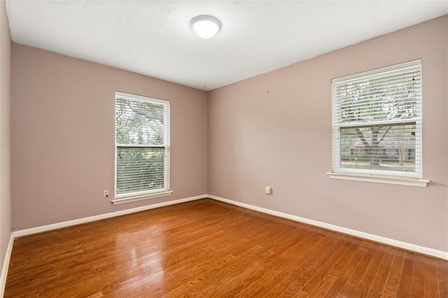 unfurnished room with baseboards and wood finished floors