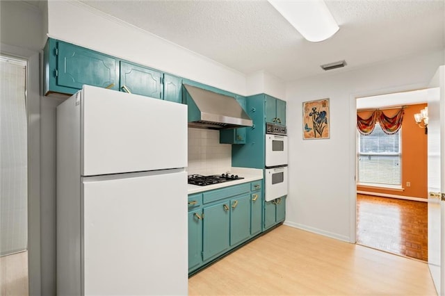 kitchen with white appliances, visible vents, decorative backsplash, wall chimney exhaust hood, and light wood-type flooring