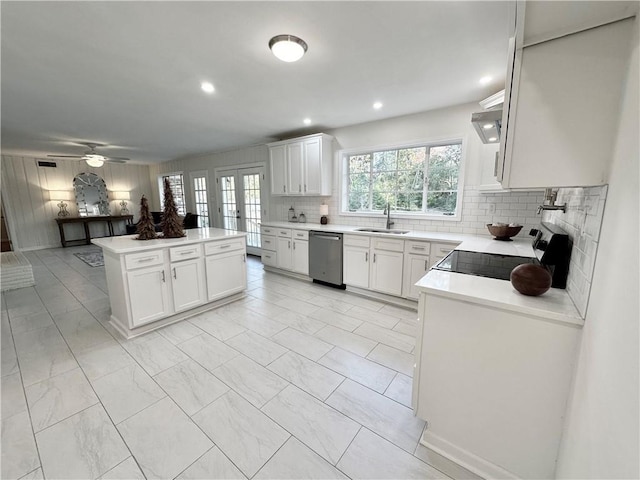 kitchen with white cabinets, tasteful backsplash, black range oven, sink, and dishwasher