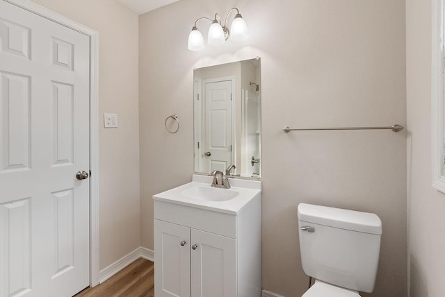 bathroom featuring wood finished floors, vanity, toilet, and baseboards