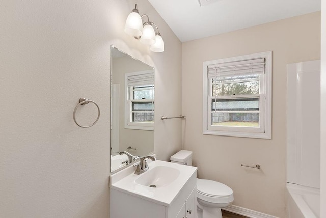 full bath featuring a healthy amount of sunlight, baseboards, toilet, and vanity