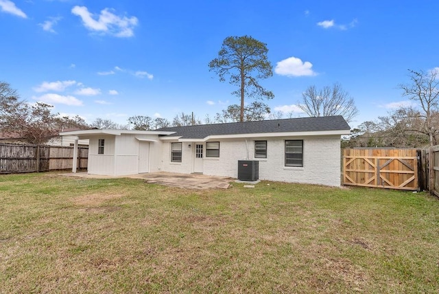 rear view of house with a fenced backyard, a lawn, and a patio