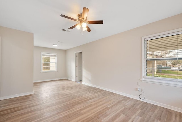 spare room featuring light wood-type flooring, baseboards, visible vents, and a ceiling fan