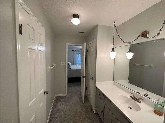 bathroom featuring connected bathroom, a textured ceiling, visible vents, baseboards, and vanity