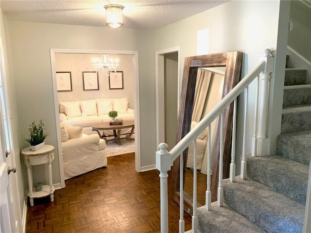 interior space featuring an inviting chandelier, a textured ceiling, and baseboards