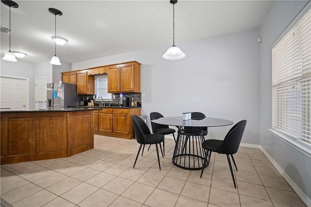 kitchen with sink, stainless steel fridge, pendant lighting, decorative backsplash, and light tile patterned flooring