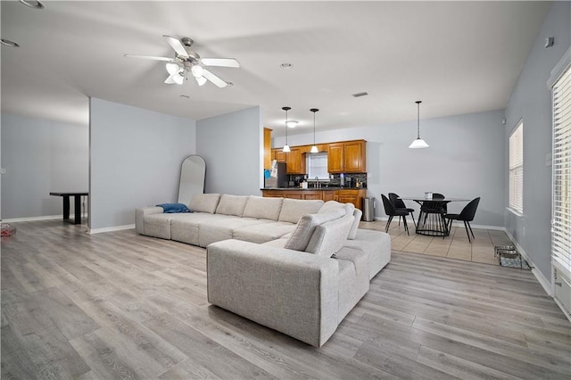 living room with ceiling fan, light hardwood / wood-style flooring, and sink