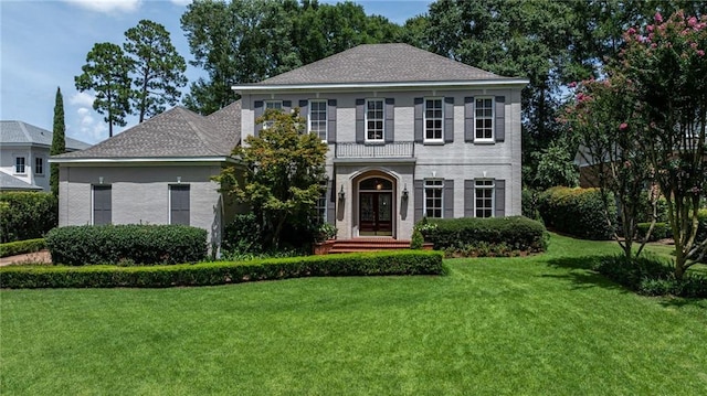 view of front facade with brick siding, french doors, and a front yard