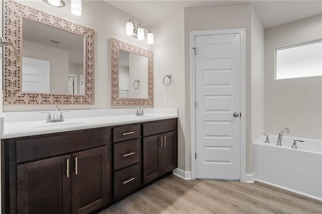 bathroom featuring hardwood / wood-style flooring, a tub to relax in, and vanity