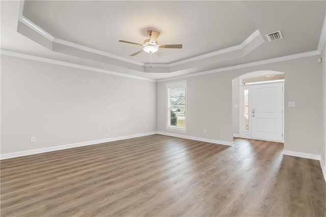 spare room with crown molding, ceiling fan, a tray ceiling, and hardwood / wood-style floors