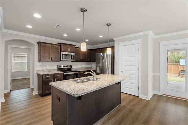 kitchen with pendant lighting, sink, appliances with stainless steel finishes, a kitchen island with sink, and a kitchen breakfast bar