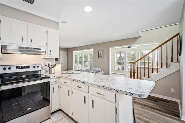 kitchen with electric stove, under cabinet range hood, a peninsula, white cabinetry, and recessed lighting