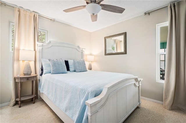 bedroom with light colored carpet, a ceiling fan, baseboards, and a textured ceiling
