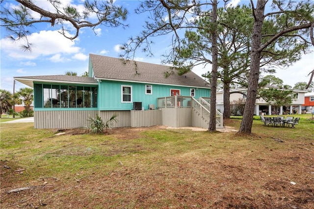 back of house featuring a sunroom, a shingled roof, stairway, and a yard